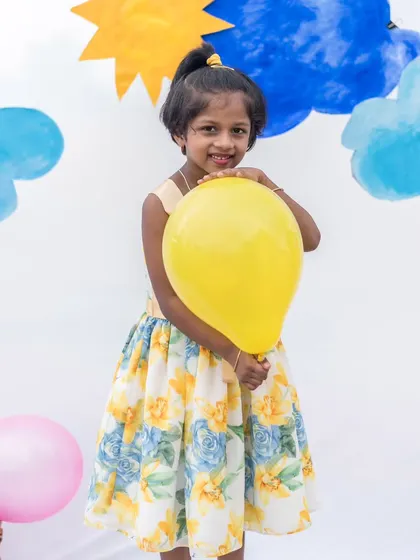 A bright and cheerful yellow floral dress, perfect for a sunny day. This photo captures the playful spirit of the dress and the happy girl wearing it.