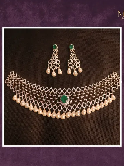This necklace is the essence of timeless elegance. A delicate web of diamonds is accented with a central emerald and drops of luminous pearls. The matching earrings feature the same emerald and pearl details.