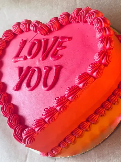A vibrant, heart-shaped cake perfect for Valentine's Day or an anniversary. The two-tone pink and orange frosting with "Love You" scripted on top makes a sweet statement.