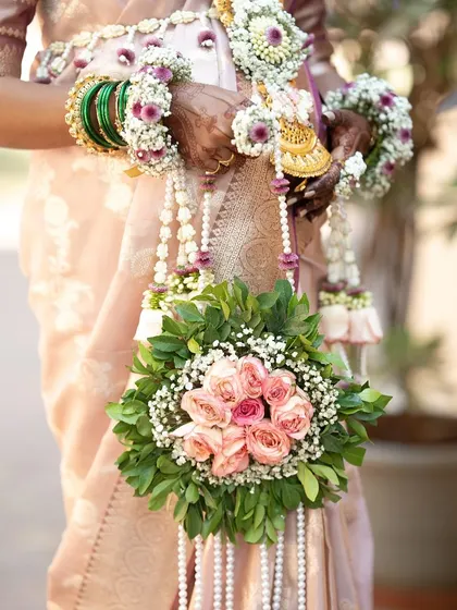 A close-up of a client holding a floral purse made with pink roses and lush greenery. This prop is designed to be held and featured in maternity photos.
