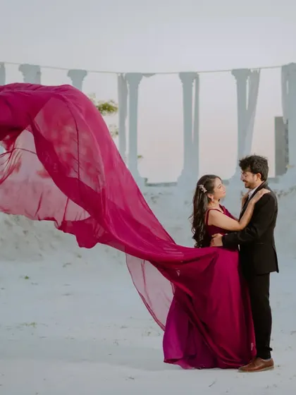 The flowing magenta gown against the white pillars of this set creates a stunning, high-fashion look. This is for couples who want a touch of editorial glamour in their pre-wedding shoot.