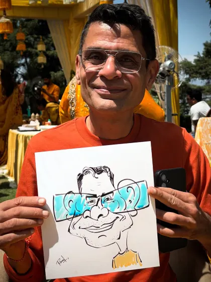 This guest is all smiles holding his cool caricature with oversized glasses. A fun moment from a sunny wedding day.