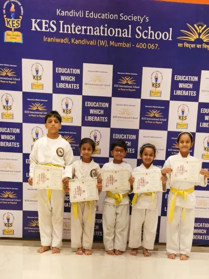 Five dedicated students from KES International School after their belt promotion. Our training helps children develop coordination, balance, and physical fitness in a structured setting.