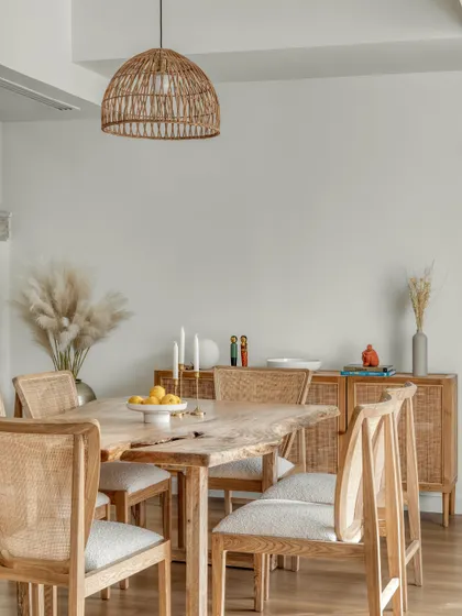 A closer look at the dining area, where natural wood and cane chairs are paired with a simple console. The light color palette and use of pampas grass add to the soft, textural quality of the space.