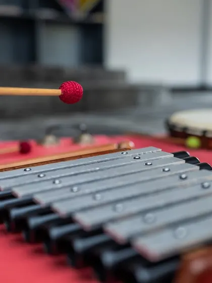 A close-up of a mallet striking a metallophone during a sound bath. The clear, resonant tones produced by this instrument help to quiet the mind and guide you into a meditative state.