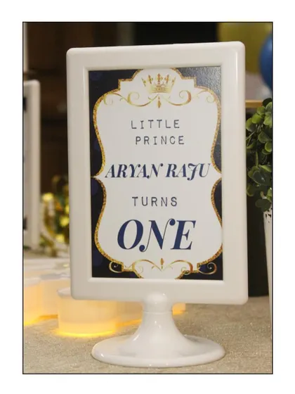 A personalized table sign for a 'Little Prince' first birthday. These custom details, featuring the child's name and elegant gold and blue designs, help tie the entire theme together.