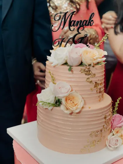 Celebrating love with this elegant two-tier anniversary cake. The combination of soft pink buttercream, delicate gold leaf, and fresh roses creates a timeless and romantic look.