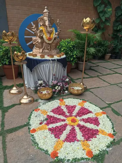 A Ganesha idol and a floral rangoli create a welcoming display for guests at a special event.