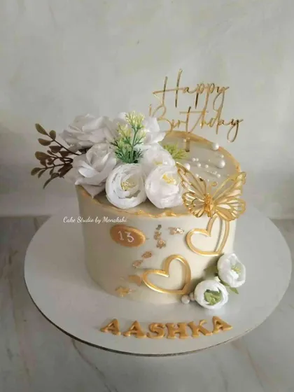 A beautiful cake to welcome the teenage years. This no-fondant design in white and gold is decorated with white flowers, a golden butterfly, and hearts for an elegant 13th birthday.