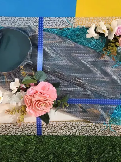 A stylish kurta set for the groom, packed in a tray with blue shredded paper and decorated with flowers. It's a simple yet elegant way to gift traditional wear.