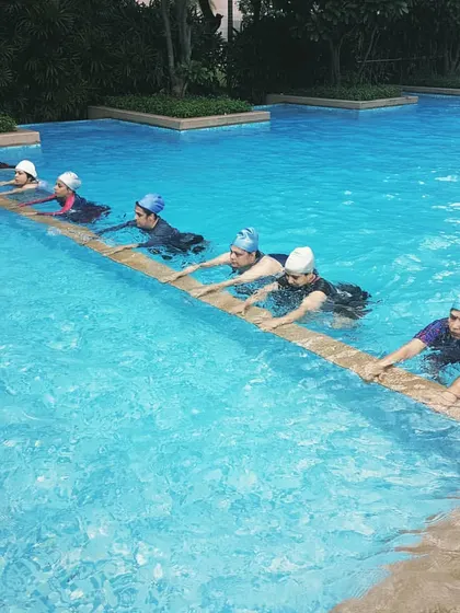 My women's batch works on leg exercises at the pool's edge. This movement helps build lower body strength and endurance with the water providing gentle resistance.