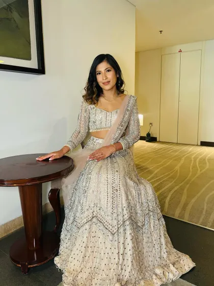 A full-length portrait of Laxmi from Nepal. She is seated, looking poised and elegant in her beautiful reception lehenga.