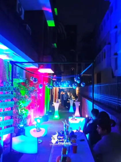 The outdoor lounge area for the neon party was filled with glowing LED cocktail tables and seating, with disco balls hanging overhead and colorful lights washing over the space.