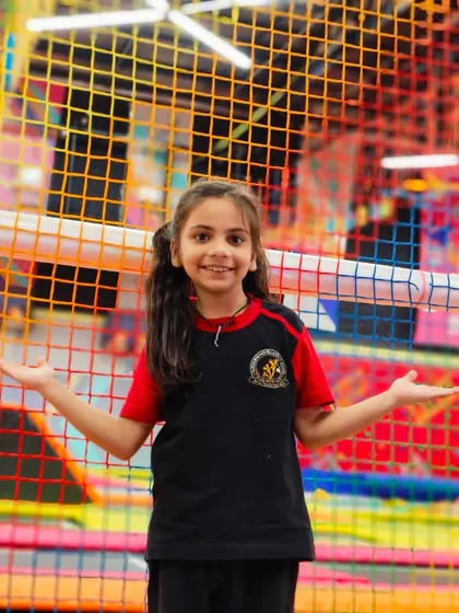 A student poses against the colorful netted background of the play area, showcasing the vibrant and safe environment.