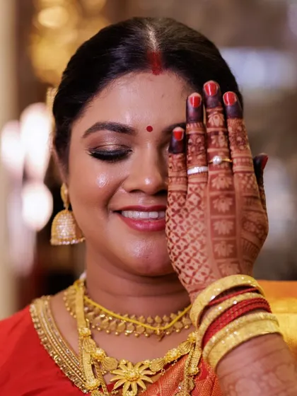 A close up showcasing the detailed eye makeup and flawless skin for the South Indian bride. The look is paired with her intricate henna design and traditional gold jewelry.