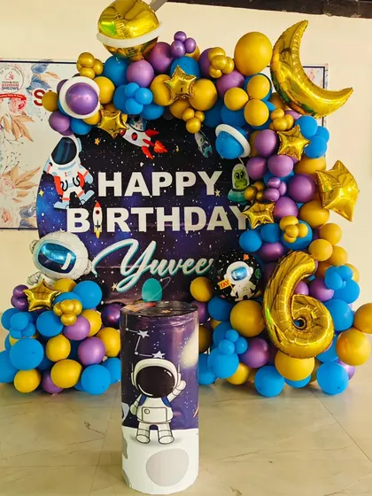 A complete space astronaut theme for a 6th birthday. This setup includes a custom backdrop, a themed pedestal, and a vibrant balloon arch with planet and rocket details.