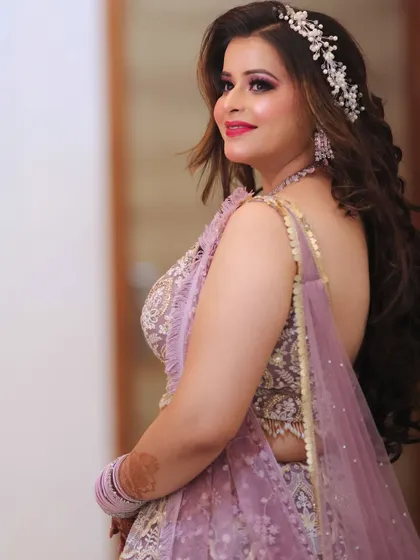 The bride looking over her shoulder with a beautiful smile. The makeup is glamorous yet elegant, with a pop of color on the lips.