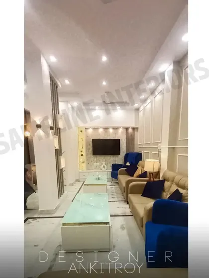 A full view of a living room we designed, featuring a long sofa arrangement, a central TV unit, and a partition on the left.