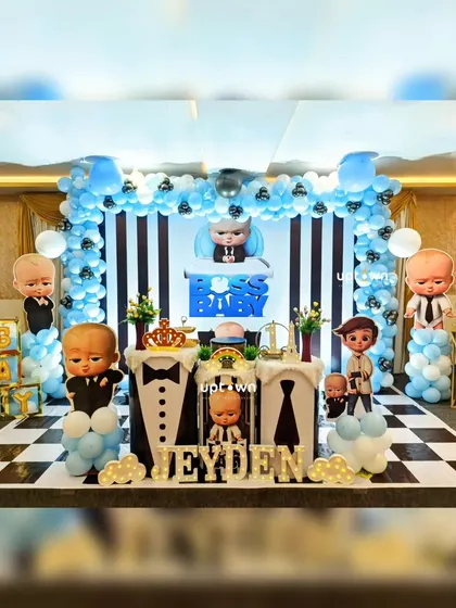 A complete Boss Baby themed stage with a black and white striped backdrop and blue balloon arch.