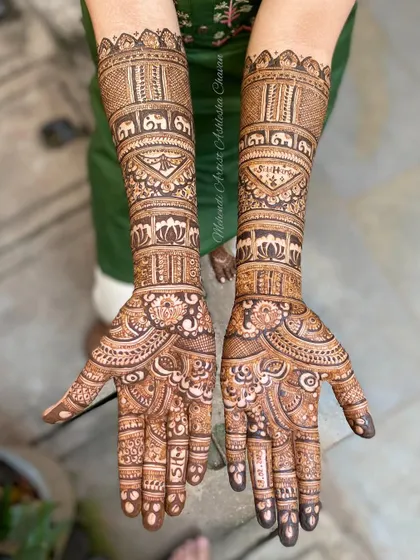 A full bridal mehendi design with personalized initials. The intricate patterns include elephants and lotus flowers, creating a beautiful and meaningful piece of art.
