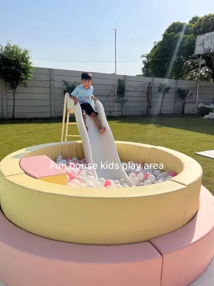 A child enjoys the slide into our pastel yellow ball pit, a key feature of this fun outdoor setup.