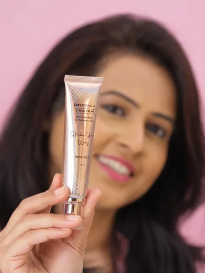 A lifestyle shot of a model holding a tube of strobe cream. The focus is on the product, but the model's presence adds a human and relatable element.