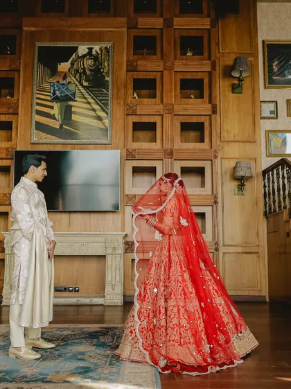 The first look. A beautifully composed shot of the groom seeing his bride for the first time, set against a warm, wood-paneled interior.