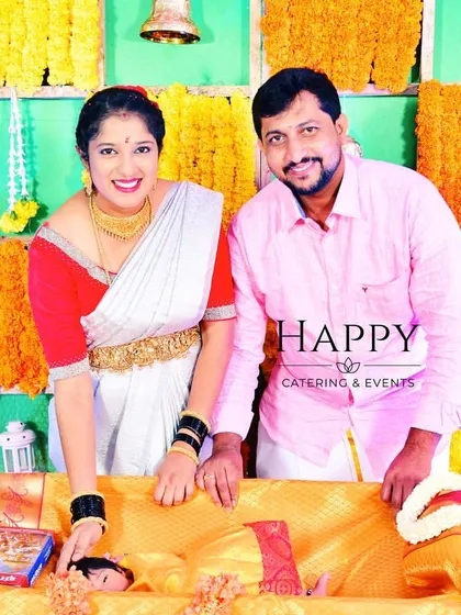Happy clients at their baby's naming ceremony, posing in front of a vibrant marigold backdrop I designed. It is my greatest joy to see families celebrate their precious moments with my decorations.