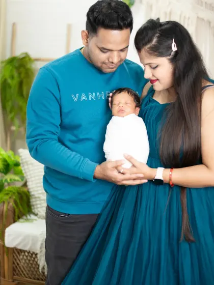 A beautiful first family portrait. The parents hold their newborn together, a perfect symbol of their new life as a family of three.
