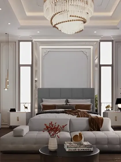 A grand and luxurious master bedroom suite featuring classic wall molding, a stunning crystal chandelier, and a separate seating area. This design exemplifies our capability in creating high-end, opulent interiors.