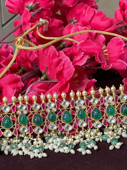 This elegant Kundan choker with green leaf-shaped stones and pearl drops is a modern and chic choice. It's perfect for a sangeet or cocktail party.