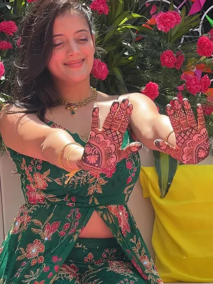 A fun, candid shot of a client enjoying her mehendi ceremony. The vibrant colors of her outfit and the decor make the henna pop.