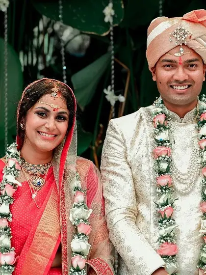A classic portrait of a smiling couple after their wedding ceremony, adorned with beautiful flower garlands.