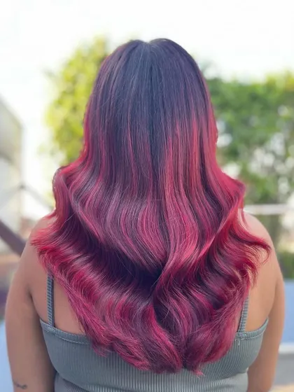 A back view of the vibrant red hair color. The long, flowing waves perfectly showcase the depth and intensity of the red tones, creating a truly show-stopping look.