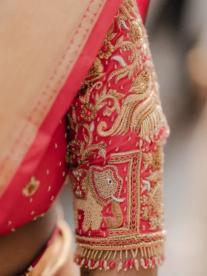 A close-up of the sleeve of the bride's blouse, featuring magnificent elephant and bird motifs in zardosi embroidery.