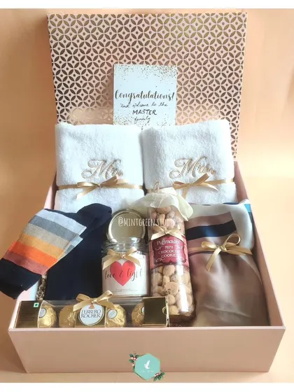 A warm welcome to the family for a new couple. This hamper includes embroidered 'Mr' and 'Mrs' towels, cozy socks, a scented candle, and gourmet nuts, making them feel loved and celebrated.