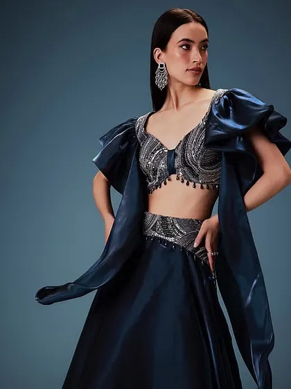 A full view of a stunning navy blue lehenga. The sleek, center-parted hair and understated makeup ensure the focus remains on the striking outfit, making it a great choice for a bridesmaid.