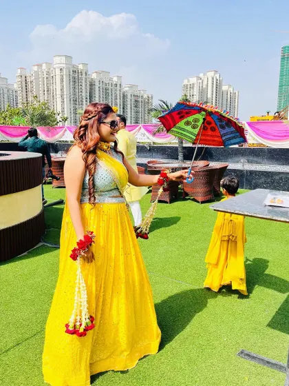 A happy client at her outdoor Haldi ceremony. The makeup is natural and radiant, perfect for a sunny day, and her braided hairstyle is both beautiful and practical.