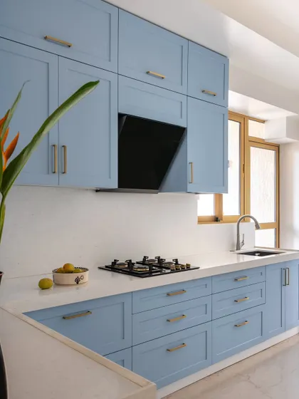 In this kitchen, we used a soft, powder blue for the cabinetry to create a calm and airy feel. The clean lines of the shaker-style cabinets are paired with a simple white countertop and a large window that fills the space with natural light.