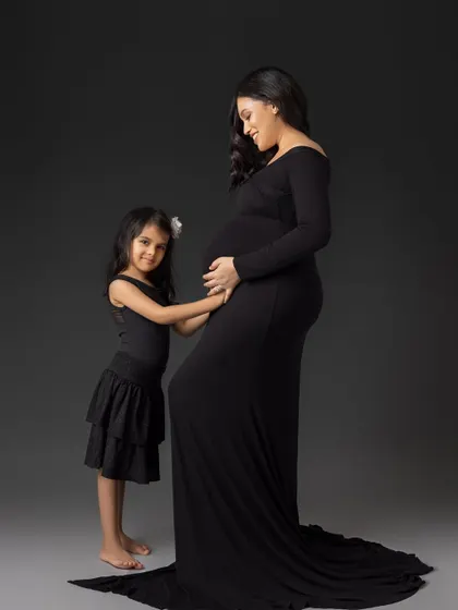 "I'm going to be a big sister." This touching portrait shows a little girl gently touching her mother's belly, a simple and powerful image of a family's growing love.