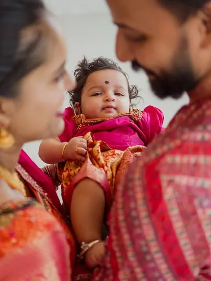 An intimate, over-the-shoulder shot showing the baby looking up at her loving parents. This perspective creates a feeling of warmth and connection, documenting the bond of a new family.
