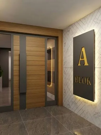 A sleek and modern apartment entrance with a wood and metal door and a backlit block number sign.