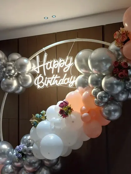 A close-up of the elegant birthday setup, highlighting the 'Happy Birthday' neon sign and the beautiful color combination of the balloons.