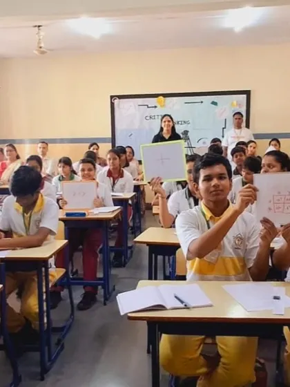 Students at a DPS school proudly holding up their work during a critical thinking session. It's wonderful to see their confidence and engagement.