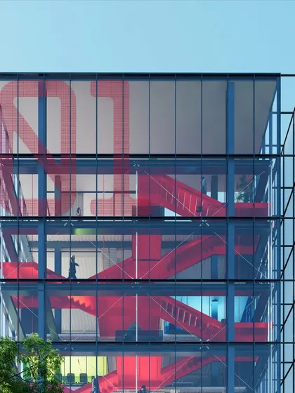A close up of the collaboration atrium in the Pune office. The red staircase is a strong visual element, symbolizing connection and movement, while the transparent glass facade fills the space with daylight and offers views of the nearby river.