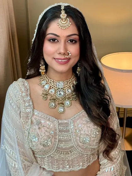 Subtle glamour for the bride who dreams in hues of love. This look features soft pink eyeshadow and a flawless base, perfectly complementing her ivory and silver lehenga.
