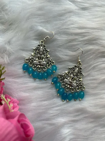 A styled shot of the silver Lakshmi earrings with blue beads, showing their vibrant colour and intricate temple design.