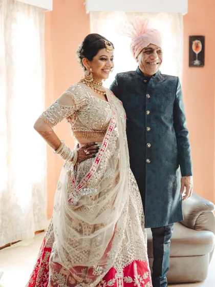 The bride posing with her proud father, a beautiful portrait that also showcases her elegant wedding attire.