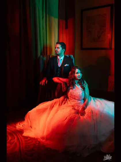 A dramatic reception portrait with colored lighting. The couple looks like characters in a romantic movie, exuding style and confidence.