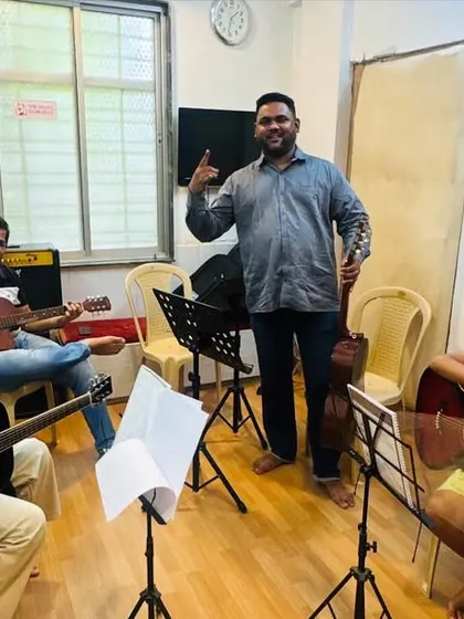 A proud moment in our guitar class. Our coach stands with his students, who are learning various techniques on both acoustic and electric guitars, fostering a fun and encouraging atmosphere.